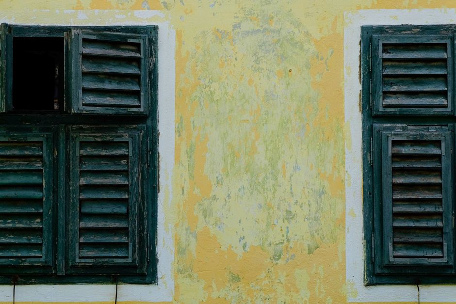 Faded yellow painted wall with wooden shutters