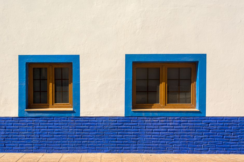 Sunlit painted wall with blue framed windows