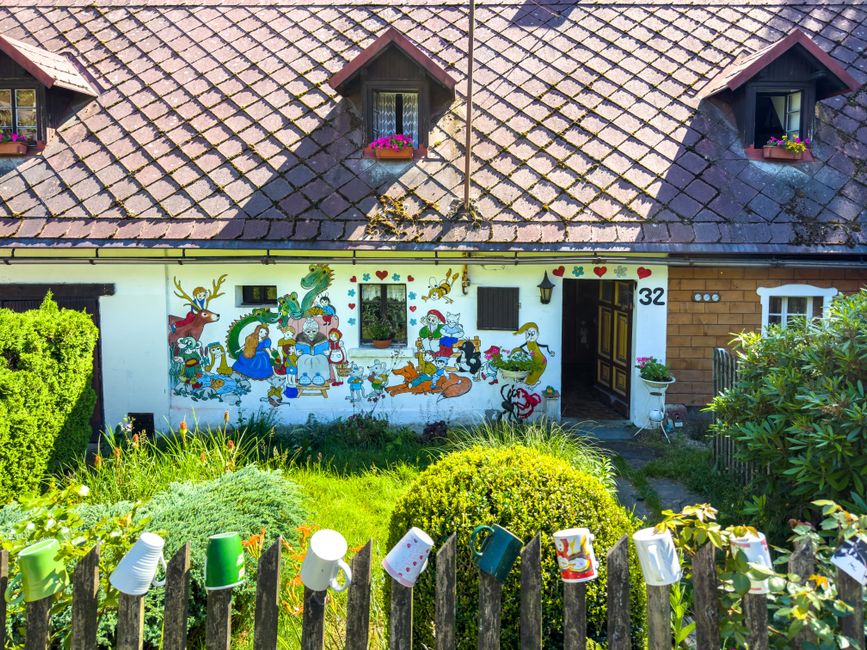 Painted house front with a colourful wall and flowers